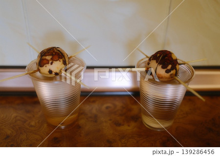 Two avocado seeds are suspended in water by toothpicks to encourage rooting in the kitchen 139286456