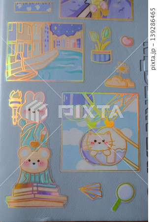Several pastel stickers with shiny edges decorate a textured light blue surface 139286465