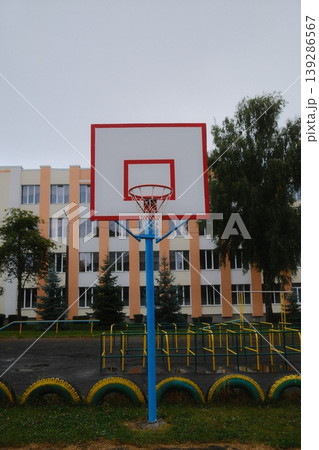 Outdoor recreation area with a basketball hoop is seen on a cloudy day near school Outdoor recreation area with a basketball hoop is seen on a cloudy day near school 139286567