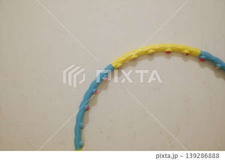 A colorful hula hoop is shown against a pale tan or off-white wall A colorful hula hoop is shown against a pale tan or off-white wall 139286888