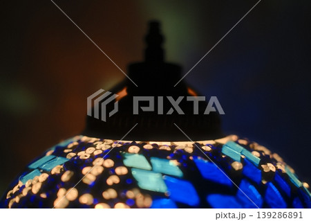 A glowing Turkish lamp features blue and white mosaics. The lamp is lit in dim light A glowing Turkish lamp features blue and white mosaics. The lamp is lit in dim light 139286891