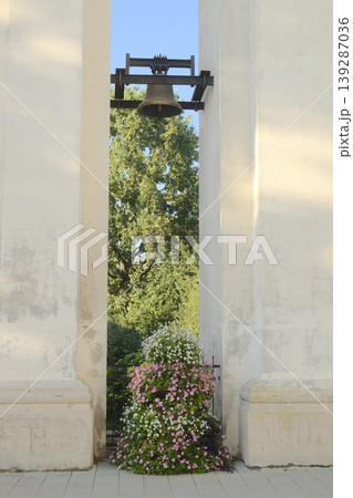 A bell hangs in a tower seen through opening, flowers at base A bell hangs in a tower seen through opening, flowers at base 139287036