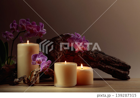 Orchid flowers and burning candles on a background of old wooden snags. Orchid flowers and burning candles on a background of old wooden snags. 139287315