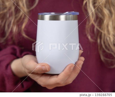 Blank white 12 oz wine tumbler mockup in hands of young woman in dark red sweatshirt, copy space 139288705