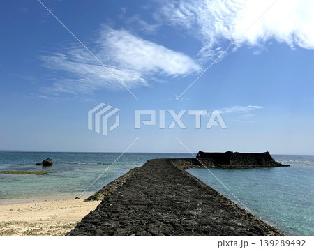 海に延びる石積みの防波堤と白砂の浜に広がる沖縄の海 海に延びる石積みの防波堤と白砂の浜に広がる沖縄の海 139289492