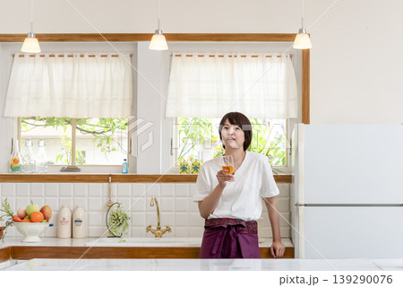 キッチンでグラスを持つ笑顔の女性 139290076