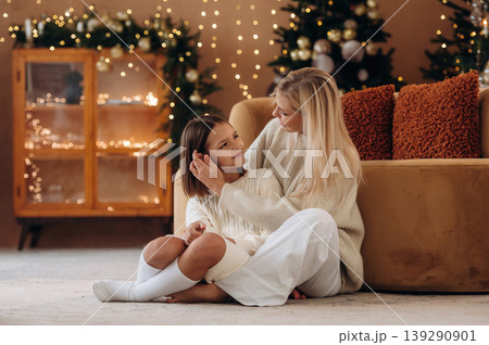 Embracing each other. Mother and daughter are celebrating New Year at home in domestic room Embracing each other. Mother and daughter are celebrating New Year at home in domestic room 139290901