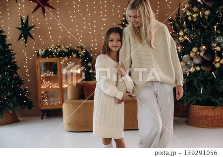 Holding the hands. Mother and daughter are celebrating New Year at home in domestic room Holding the hands. Mother and daughter are celebrating New Year at home in domestic room 139291056