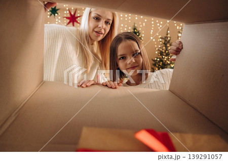 View from the inside of box. Mother and daughter are looking at the New Year presents View from the inside of box. Mother and daughter are looking at the New Year presents 139291057