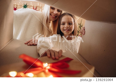 Bright garlands. View from the inside of box. Mother and daughter are looking at the New Year presents Bright garlands. View from the inside of box. Mother and daughter are looking at the New Year presents 139291064