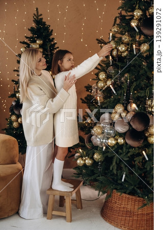 Helping to decorate the tree. Mother and daughter are celebrating New Year at home in domestic room 139291072
