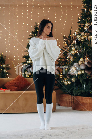 Model is in warm clothes. Woman is celebrating New Year at home in the cozy room with Christmas decorations 139291125