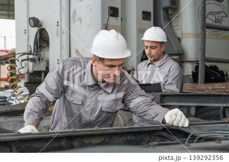 Caucasian and Middle Eastern mid-adult male mechanics repairing truck engine with laptop in Asian yard 139292356