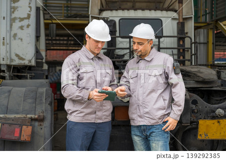 Caucasian and Middle Eastern mid-adult male mechanics using tablet by truck in Asian industrial yard Caucasian and Middle Eastern mid-adult male mechanics using tablet by truck in Asian industrial yard 139292385