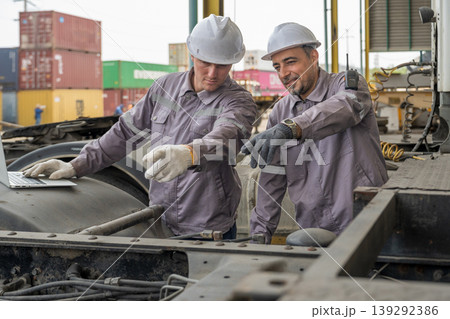 Caucasian and Middle Eastern mid-adult male mechanics repairing truck engine with laptop in Asian yard 139292386