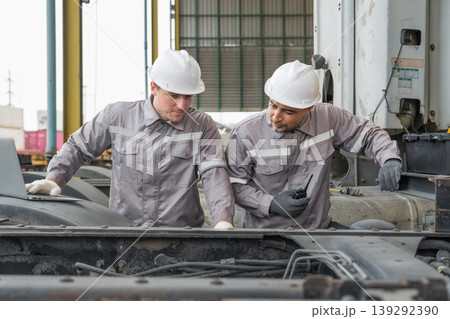 Caucasian and Middle Eastern mid-adult male mechanics repairing truck engine with laptop in Asian yard 139292390