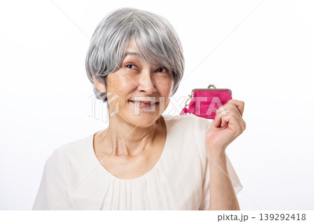 ピンク色のがま口を片手にニヤニヤするシニア女性 ピンク色のがま口を片手にニヤニヤするシニア女性 139292418