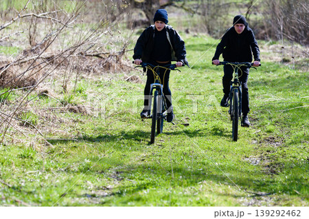 Two boys biking on a grassy trail, enjoying a sunny day outdoors. A fun adventure on two wheels 139292462
