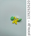 Top view of a small pile of green, yellow, and white medicine pills scattered on a plain white background 139292620