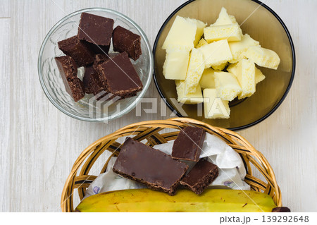 Dark and white chocolate with banana in a basket on a table. Dark and white chocolate with banana in a basket on a table. 139292648