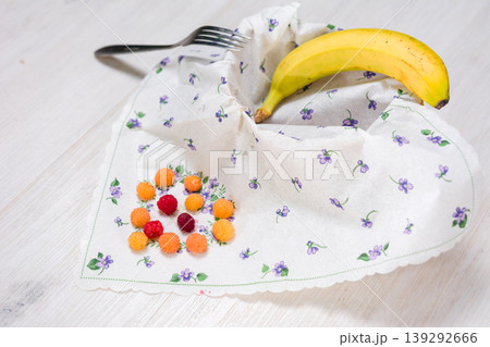 Fruit, berries, and a fork arranged on a floral napkin. 139292666