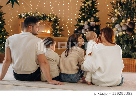 Rear view, from back. Happy family is celebrating the Christmas in the holidays decorated room Rear view, from back. Happy family is celebrating the Christmas in the holidays decorated room 139293382