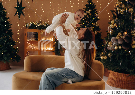 In a cozy room. Mother is with her little baby daughter are indoors, celebrating Christmas 139293812