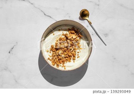 Balanced breakfast with yogurt, granola and spoon on marble background. Top view Balanced breakfast with yogurt, granola and spoon on marble background. Top view 139293849