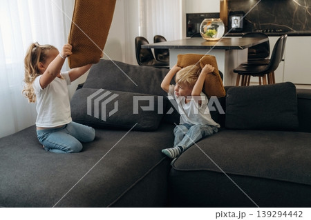 Boy and girl are playing on the black sofa at home, having fun Boy and girl are playing on the black sofa at home, having fun 139294442