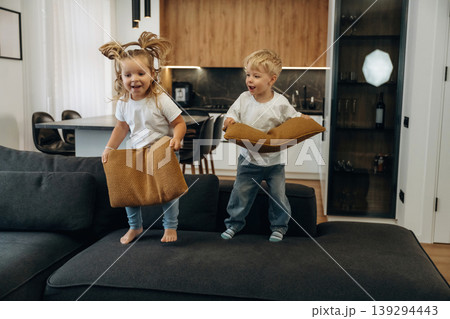 Boy and girl are playing on the black sofa at home, having fun 139294443