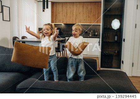 Boy and girl are playing on the black sofa at home, having fun Boy and girl are playing on the black sofa at home, having fun 139294445