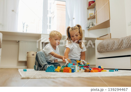 Red, blue, yellow colored objects. Two kids are playing with construction blocks toys at home 139294467