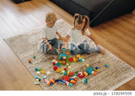 Sitting on the modern carpet. Two kids are playing with construction blocks toys at home 139294509
