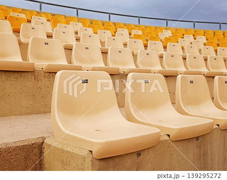 Empty Stadium Seats in Yellow and White Rows Under Cloudy Sky 139295272