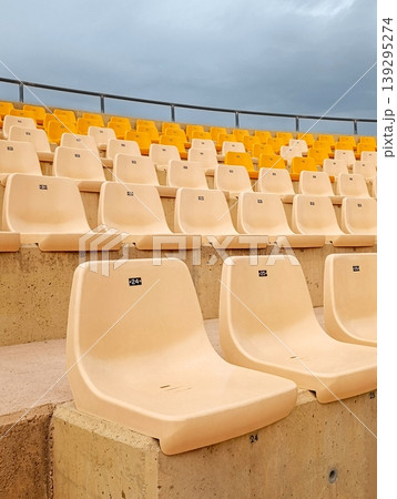 Empty Bleachers with Yellow and White Chairs Under Overcast Sky 139295274