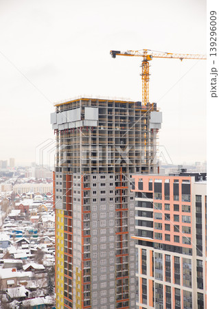 Construction of a modern high-rise building with crane in a snowy urban landscape during winter 139296009