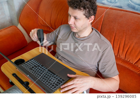 Man cleaning laptop keyboard with mini turbo fan air duster. Portable handheld blower for contactless device maintenance and dust removal from computer cooling system and electronics. 139296085