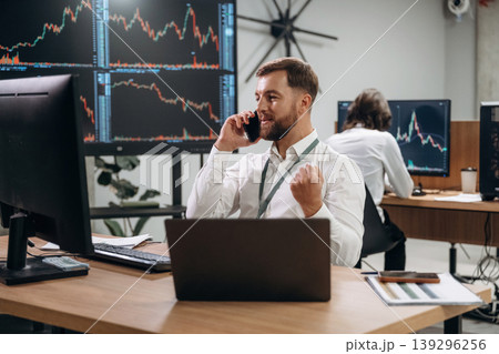 Phone call, talking. Two male exchange workers are in the office together Phone call, talking. Two male exchange workers are in the office together 139296256