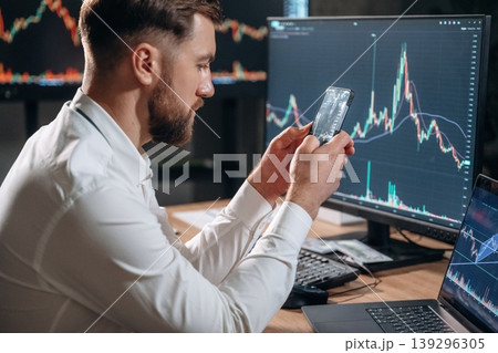 Handsome businessman is in the office with stock exchange market information on displays 139296305
