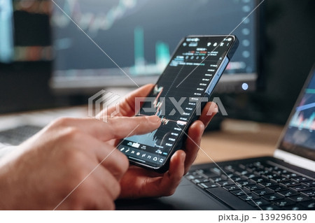 Detailed close up view of man's hands that is holding smartphone with stock market crypto information 139296309