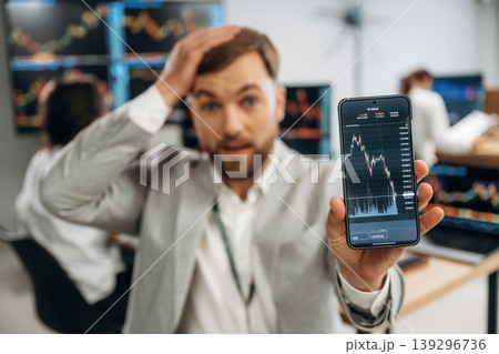 Worrying, showing graph on phone. Business people are working with stock market exchange in office 139296736