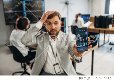 Worrying, showing graph on phone. Business people are working with stock market exchange in office 139296737