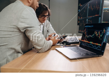 Focused at work, analyzing the data. Two male exchange workers are in the office together Focused at work, analyzing the data. Two male exchange workers are in the office together 139296820