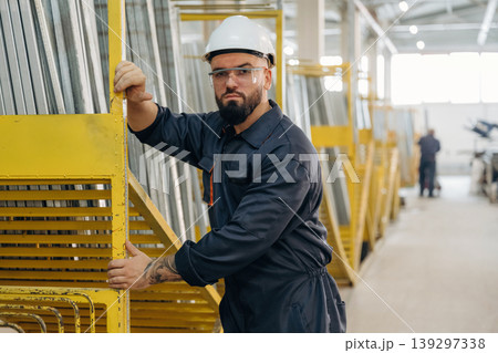 Row of yellow colored parts. Warehouse worker in an industrial environment of a factory or storage area 139297338