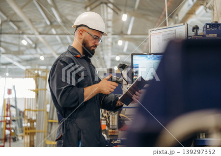 Machine operator is with notepad. Warehouse worker in an industrial environment of a factory or storage area Machine operator is with notepad. Warehouse worker in an industrial environment of a factory or storage area 139297352