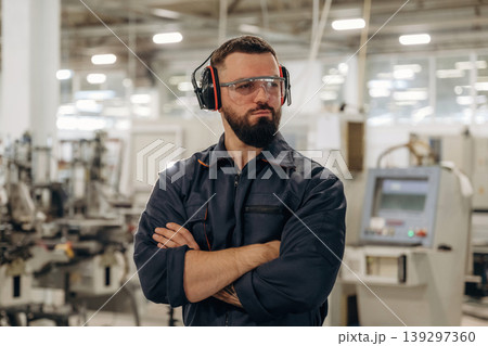 Break time, standing with arms crossed. Warehouse worker in an industrial environment of a factory or storage area Break time, standing with arms crossed. Warehouse worker in an industrial environment of a factory or storage area 139297360