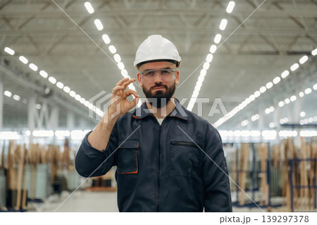 Guy is standing and posing. Warehouse worker in an industrial environment of a factory or storage area Guy is standing and posing. Warehouse worker in an industrial environment of a factory or storage area 139297378