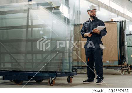Glass is ready to put in windows. Warehouse worker in an industrial environment of a factory or storage area Glass is ready to put in windows. Warehouse worker in an industrial environment of a factory or storage area 139297421