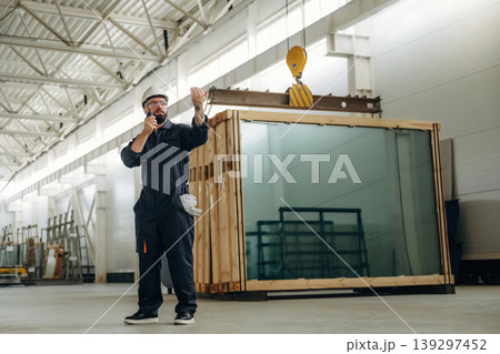 Talking by walkie talkie. Warehouse worker in an industrial environment of a factory or storage area 139297452