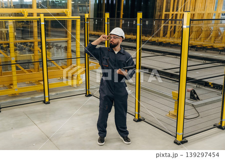 Holding digital tablet. Warehouse worker in an industrial environment of a factory or storage area 139297454